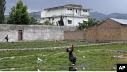 FILE - A boy plays with a tennis ball in front of Osama bin Laden's compound in Abbottabad, Pakistan, May 2011. Osama bin Laden was killed at his compound on May 2, 2011, by a U.S. special forces team.