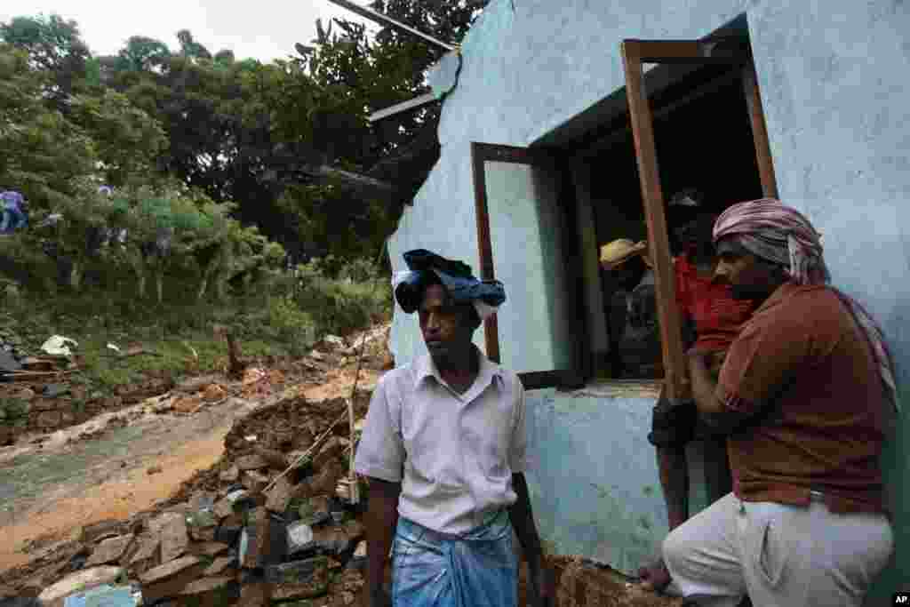 Sri Lankan men stand by their damaged house caused by a mudslide at the Koslanda tea plantation in the Badulla district, Sri Lanka, Oct. 29, 2014. 