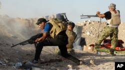 Iraqi security forces defend their positions against an Islamic State group attack in Husaybah, Iraq, June 15, 2015. 