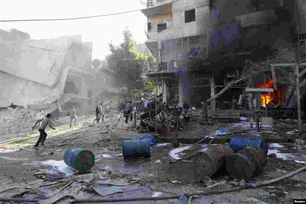 Residents run after activists said two barrel bombs were thrown by forces loyal to President Bashar Al-Assad in Aleppo, May 1, 2014.