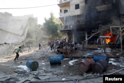 Residents run after activists said two barrel bombs were thrown by forces loyal to Syria's president Bashar Al-Assad in Aleppo, May 1, 2014.