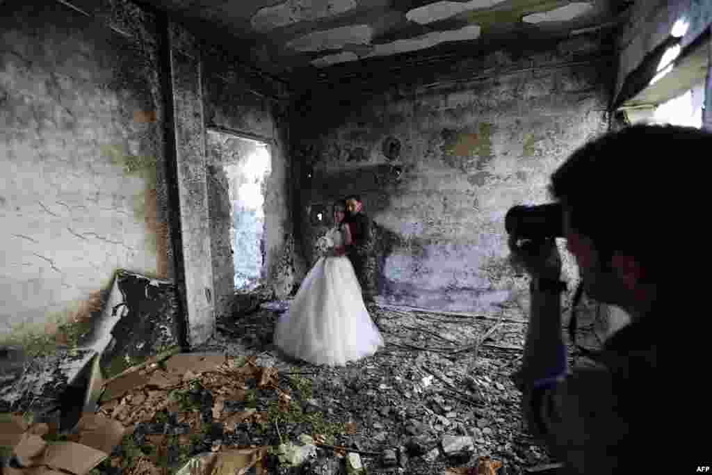 Pasangan Suriah yang baru menikah Nada Merhiand Hassan Youssef difoto di gedung yang rusak berat di kota Homs yang dirundung perang. Seorang fotografer Suriah menggunakan latar belakang kota Homs yang rusak untuk menunjukkan bahwa kehidupan lebih kuat daripada kematian.