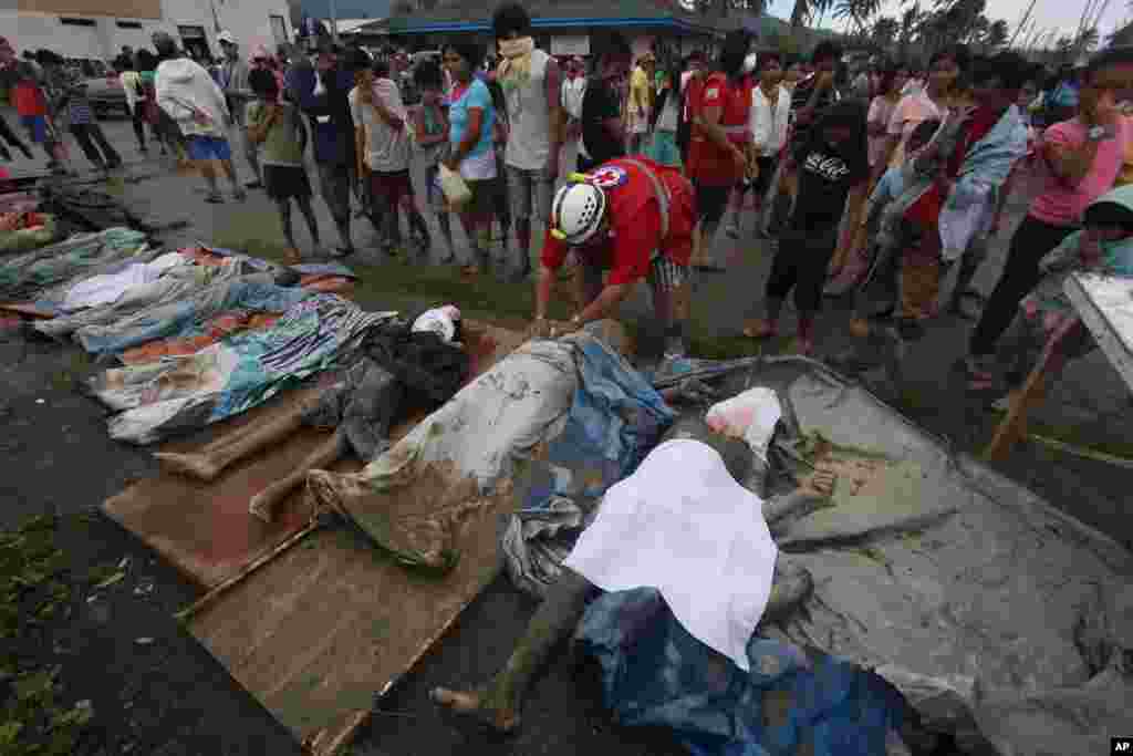菲律宾南部孔波斯特拉省新巴丹镇发生山洪爆发后，一名援救人员2012年12月5日给寻获的遇难者覆盖尸布