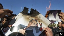 Protesters burn a photo of former Tunisian President Zine El Abidine Ben Ali during a demonstration in Tunis, 24 Jan 2011