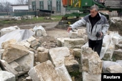 FILE - A Bosnian construction worker shows remains of the blown up Ferhadija mosque in Banja Luka, Dec. 10, 2008.