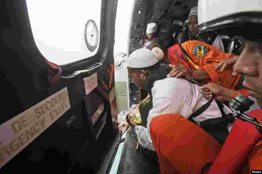A Muslim cleric scatters flowers after a prayer for victims of AirAsia Flight 8501 inside an Indonesian Air Force NAS 332 Super Puma helicopter flying over the Java Sea off Pangkalan Bun, Indonesia, Jan. 6, 2015.