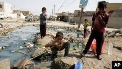 FILE - An Iraqi boy is seen drinking water from a broken pipe in Baghdad's Sadr City, Iraq.