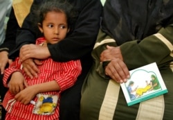 A woman holds a card in her lap about the problems with female genital mutilation (FGM) during a session to educate women in Minia, Egypt June 13, 2006.