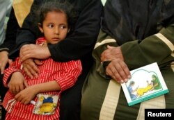 A woman holds a card in her lap about the problems with female genital mutilation (FGM) during a session to educate women in Minia, Egypt June 13, 2006.