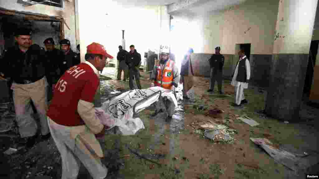 Rescue workers carry the covered body parts of a suspected suicide bomber at the site of bomb blast in a judicial compound in Peshawar, March 18, 2013.