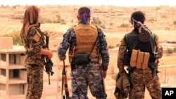 FILE -- A photo provided by the Syrian Democratic Forces (SDF) shows fighters from the SDF looking toward the northern town of Tabqa, Syria, April 30, 2017.