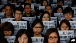Staff members of the Mingpao newspaper hold their newspaper, with the headline on the former editor Kevin Lau, who was assaulted and injured, during a protest outside the Mingpao office in Hong Kong, Feb. 27, 2014. 