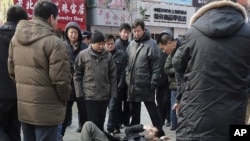 Unidentified men surround a foreign journalist after they pushed him to the ground in the shopping street of Wangfujing, after calls for a "Jasmine Revolution" protest, organized through the internet, in Beijing, February 27, 2011