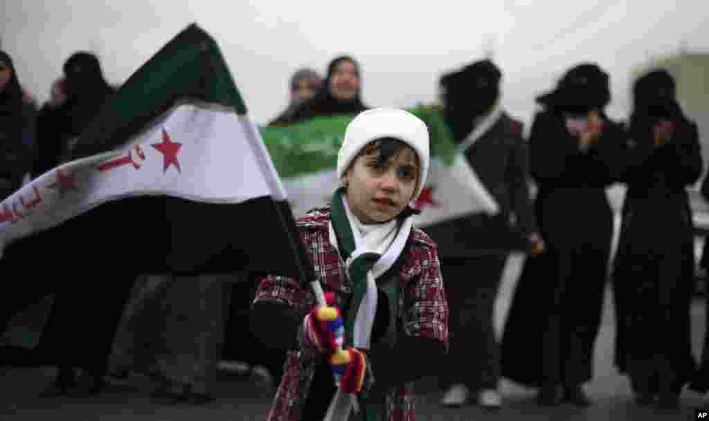 A girl waves the revolutionary Syrian flag during a protest against President Bashar al-Assad in front of the Syrian embassy to commemorate the 31st anniversary of the 1982 Hama massacre, in Amman, Jordan, February 1, 2013.