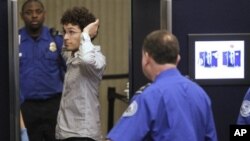 A traveler, second from left, takes a position in front of a full-body scanner as Transportation Security Administration officers look on at Boston's Logan International Airport, 22 Nov 2010