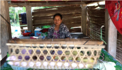 Ouk Sokha, 58, rocks her 11th grandson, who is two-and-a-half months old. She feeds her grandson baby formula while his mom works at a factory, at Svay Ta Yean commune, Svay Rieng province, Cambodia, Oct. 11, 2019. (Khan Sokummono/VOA Khmer)