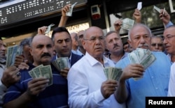 Businessmen holding U.S. dollars stand in front of a currency exchange office in response to the call of Turkish President Tayyip Erdogan on Turks to sell their dollar and euro savings to support the lira, in Ankara, Aug. 14, 2018.