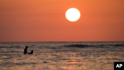 The sun sets off Waikiki Beach, in Honolulu, Hawaii on Dec. 31, 2013. Scientists expect to see fewer clouds in a warmer world as carbon emissions rise.