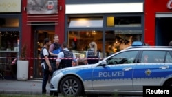 Police stand outside where a 21-year-old Syrian refugee killed a woman with a machete and injured two other people in the city of Reutlingen, Germany, July 24, 2016.