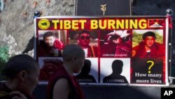 Tibetan Buddhist nuns look at a poster showing pictures of those who self-immolated since March in Tibet after a prayer session led by the Dalai Lama in Dharmsala, India, Wednesday, Oct. 19, 2011. The prayer session was to remember Tibetans who immolated 