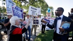 Minister Martez Thompson, right, faces backers of GOP presidential nominee Donald Trump demonstrating during Democratic rival Hillary Clinton’s campaign stop at Wayne State University in Detroit, Mich., Oct. 10, 2016.