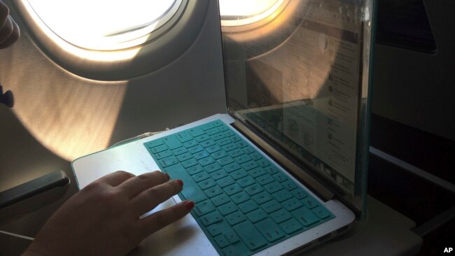 FILE - A passenger uses a laptop aboard a commercial airline flight from Boston to Atlanta on July 1, 2017.