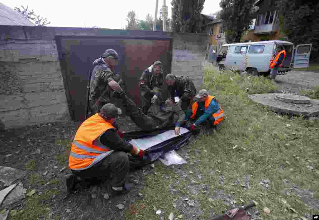 Rescue workers and pro-Russian rebels carry the body of man who was killed during shelling in Donetsk, eastern Ukraine, Oct. 1, 2014.