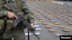 FILE - A Colombian police officer stands guard near packs of marijuana seized in Cali, March 30, 2015. Colombian narcotics police seized 4.1 tons of marijuana from drug trafficking gangs in two houses in Corinto, Cauca, according to authorities. 