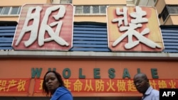FILE - An African man and woman walk outside a clothing wholesale market in Guangzhou, China, Aug. 26, 2013. 