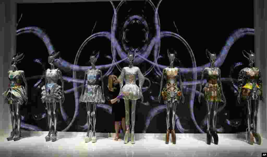 A staffmember looks at a selection of dresses from Alexander McQueen&#39;s &#39;Plato&#39;s Atlantis&#39; 2010 Spring/Summer collection at the Alexander McQueen exhibition &#39;Savage Beauty&#39; at the Victoria and Albert museum in London.