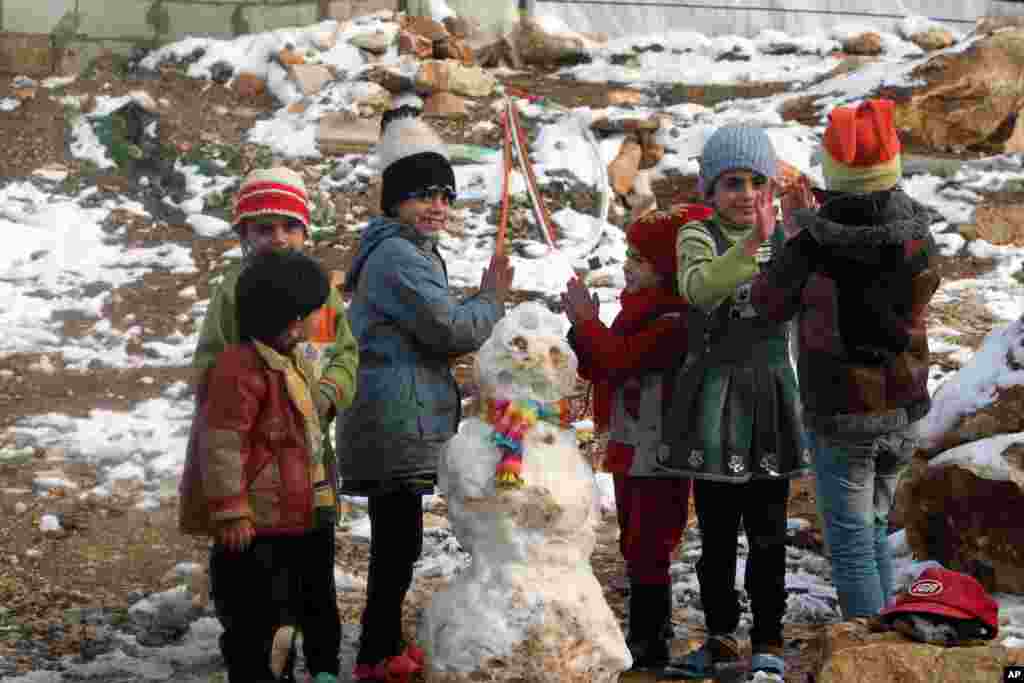 Syrian refugees children play near a snowman in a camp for Syrians who fled their country&rsquo;s civil war, in the Bekaa valley, eastern Lebanon. 