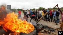 FILE: Protestors gather near a burning tire during a demonstration over the hike in fuel prices in Harare, Zimbabwe, Tuesday, Jan. 15, 2019. A Zimbabwean military helicopter on Tuesday fired tear gas at demonstrators blocking a road and burning tires in the capital.