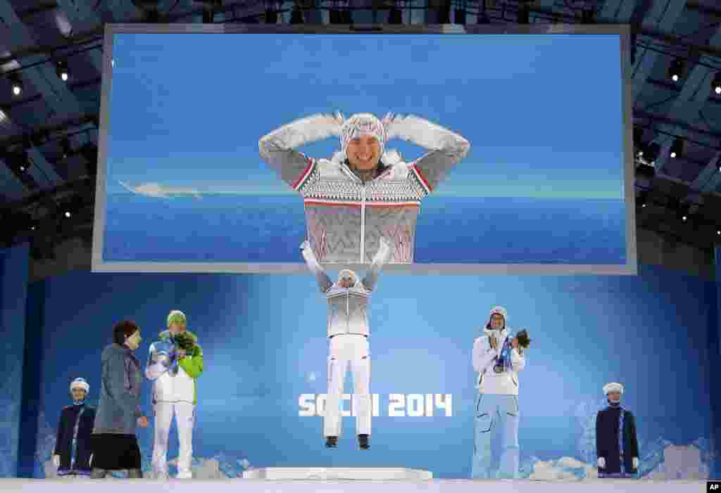 Men&#39;s normal hill ski jumping gold medalist Poland&#39;s Kamil Stoch, jumps on the podium as sliver medalist Slovenia&#39;s Peter Prevc, and bronze medalist Norway&#39;s Anders Bardal, applaud during their medals at the 2014 Winter Olympics in Sochi, Russia.