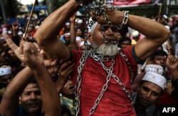 Ethnic Rohingya Muslim refugees shout slogans as they carry a man in chains during a protest against the persecution of Rohingya Muslims in Myanmar, outside the Myanmar Embassy in Kuala Lumpur.