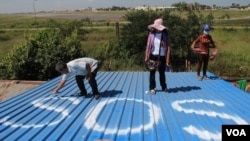 S.O.S. is the international call for help. These people in Cambodia write "SOS" on a roof so that planes flying overhead will see it and send help. (Nov. 2014 PHOTO by Povleakhena/VOA Khmer)