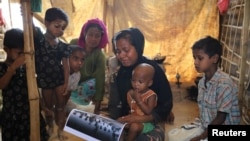 지난해 9월 라카인주 인 딘 마을에서 미얀마군에게 살해당한 로힝야족 남성 10명 중 한 명의 가족이 10일 고인의 사진을 보며 눈물을 흘리고 있다. 