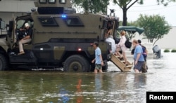 People are rescued from floodwaters from Hurricane Harvey in an armored police mine-resistant ambush protected (MRAP) vehicle in Dickinson, Texas, Aug. 27, 2017.