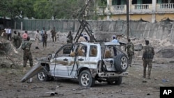 Soldiers stand near the wreckage of a car bomb attack that targeted a checkpoint in Mogadishu, Somalia, March 21, 2017. 