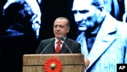 Turkey's President Recep Tayyip Erdogan delivers a speech backdropped by an image of Turkey's founding father Mustafa Kemal Ataturk, right, during a ceremony to mark the 79th anniversary of Ataturk's death, in Ankara, Turkey, Nov. 10, 2017.