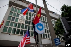 A man installs flags of North Korea, the U.S and Vietnam on a post in a street neighboring Government Guesthouse and the Metropole hotel ahead of the North Korea-U.S. summit in Hanoi, Vietnam, Feb. 25, 2019.