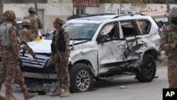 Pakistan paramilitary troops gather next to a damaged vehicle at the site of a suicide bombing in Quetta, Pakistan, Saturday, Nov. 25, 2017.