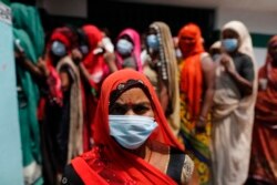 People wait to cast their votes during local panchayat elections on the outskirts of Prayagraj, in the northern Indian state of Uttar Pradesh, Thursday, April 15, 2021. India reported more than 200,000 new coronavirus cases Thursday.