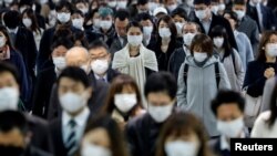 Orang-orang mengenakan masker wajah di Stasiun Shinagawa station saat jam sibuk di tengah pandemi virus corona (Covid-19) di Tokyo, Jepang, 20 April 2020.