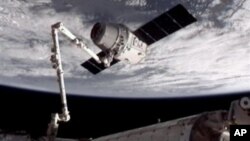 Foto yang dirilis oleh NASA-TV ini memperlihatkan Kapsul Dragon SpaceX (atas) saat ditangkap oleh tangan robot Canadarm2. Tangan robot ini merapatkan Kapsul Dragon ke Stasiun Antariksa Internasional (ISS), Jum'at (25/5).