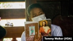 FILE - A Karen woman holds up a hymn book during Christian mass gathering, Umphang, Thailand, May 23, 2021.