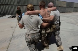 FILE - A U.S. Marine wounded in an IED attack, having been evacuated from the battlefield by the 101st Airborne, in an IED attack, is helped into the trauma bay at an advanced U.S. military field hospital at Forward Operating Base Dwyer, in southern Afghanistan.