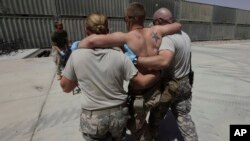 FILE - A U.S. Marine wounded in an IED attack, having been evacuated from the battlefield by the 101st Airborne, in an IED attack, is helped into the trauma bay at an advanced U.S. military field hospital at Forward Operating Base Dwyer, in southern Afgha