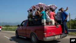 Joel Eduardo Espinar stands on the bumper of a truck as his family and others arrive in Arriaga, Mexico. Four of Espinar's friends in Honduras died from stabbings, and his wife was robbed twice at knifepoint.