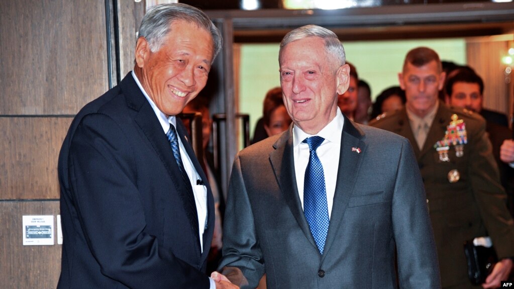 BTQP Singapore Ng Eng Hen (trái) chào đón vị tương nhiệm Mỹ James Mattis tới dự một buổi họp trước hội nghị an ninh ASEAN tại Singapore vào ngày 18/10/2018. (Photo by Roslan RAHMAN / AFP)