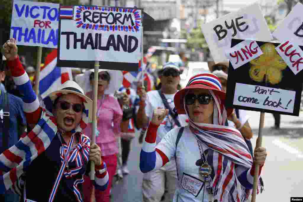 Anti-government protesters carry signs against ousted Prime Minister Yingluck Shinawatra as they march in central Bangkok, May 8, 2014.